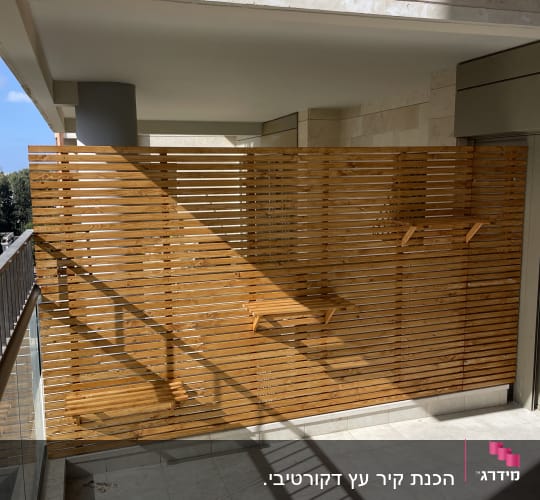 גדר עץ עם מדפים קטנים במרפסת מוארת